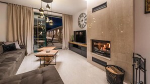 A modern living room with a sofa, a coffee table, a TV, and a fireplace.
