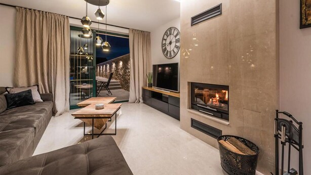 A modern living room with a sofa, a coffee table, a TV, and a fireplace. - Luxurious home in Poljaci (Poljaci)