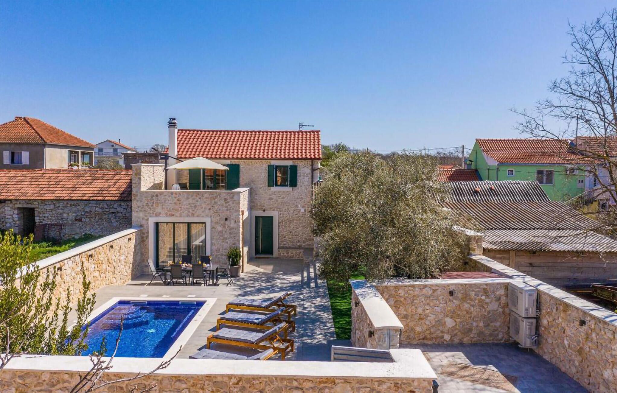 A villa with a swimming pool, outdoor seating, and stone walls.