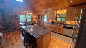 A spacious kitchen with wooden cabinets, granite countertops, and a large island with bar stools.