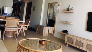 Una sala de estar moderna con mobiliario de mimbre, una mesa de centro de cristal y un televisor de pantalla plana montado en la pared.