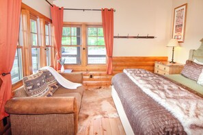 A cozy room with a bed, a chair, a small table, and a window with curtains. - EML 7 Cloven-Hoofed (Paonia)