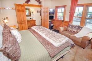 A cozy room with a bed, a sofa, a television, and a wooden door. - EML 7 Cloven-Hoofed (Paonia)