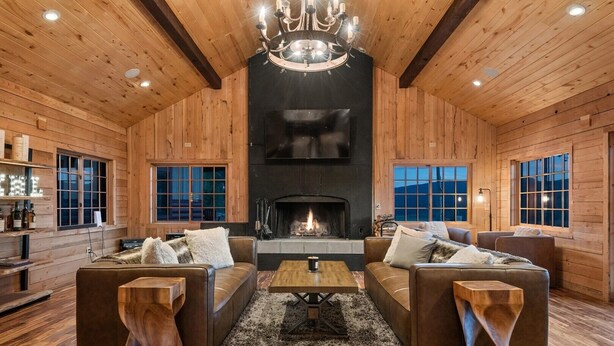 A cozy log cabin interior with a fireplace, wooden walls, and two sofas facing each other. - EML 7 Cloven-Hoofed (Paonia)