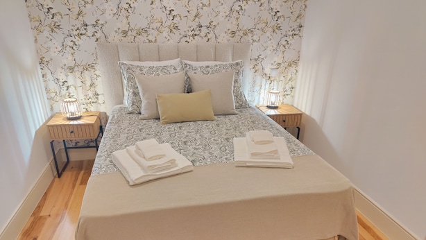A neatly made bed with a patterned bedspread, two pillows, and folded towels on the bed. - Premium Apartment Porto Downtown, With Terrace (Porto)