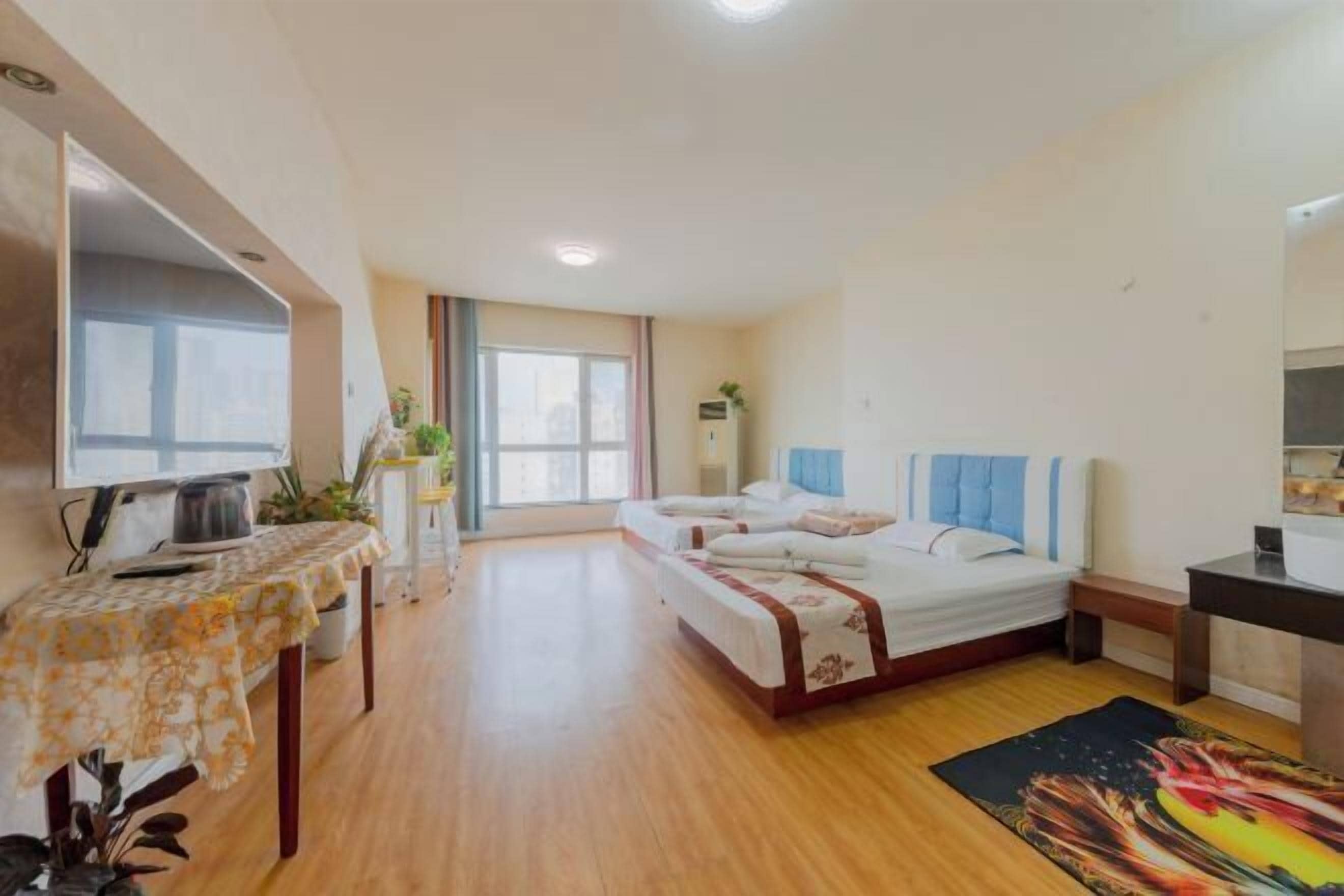 Een hotelkamer met twee bedden, een eettafel, een televisie en een raam met gordijnen.