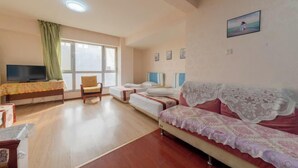 Ein Zimmer mit einem Bett, einem Sofa, einem Fernseher und einem Fenster.