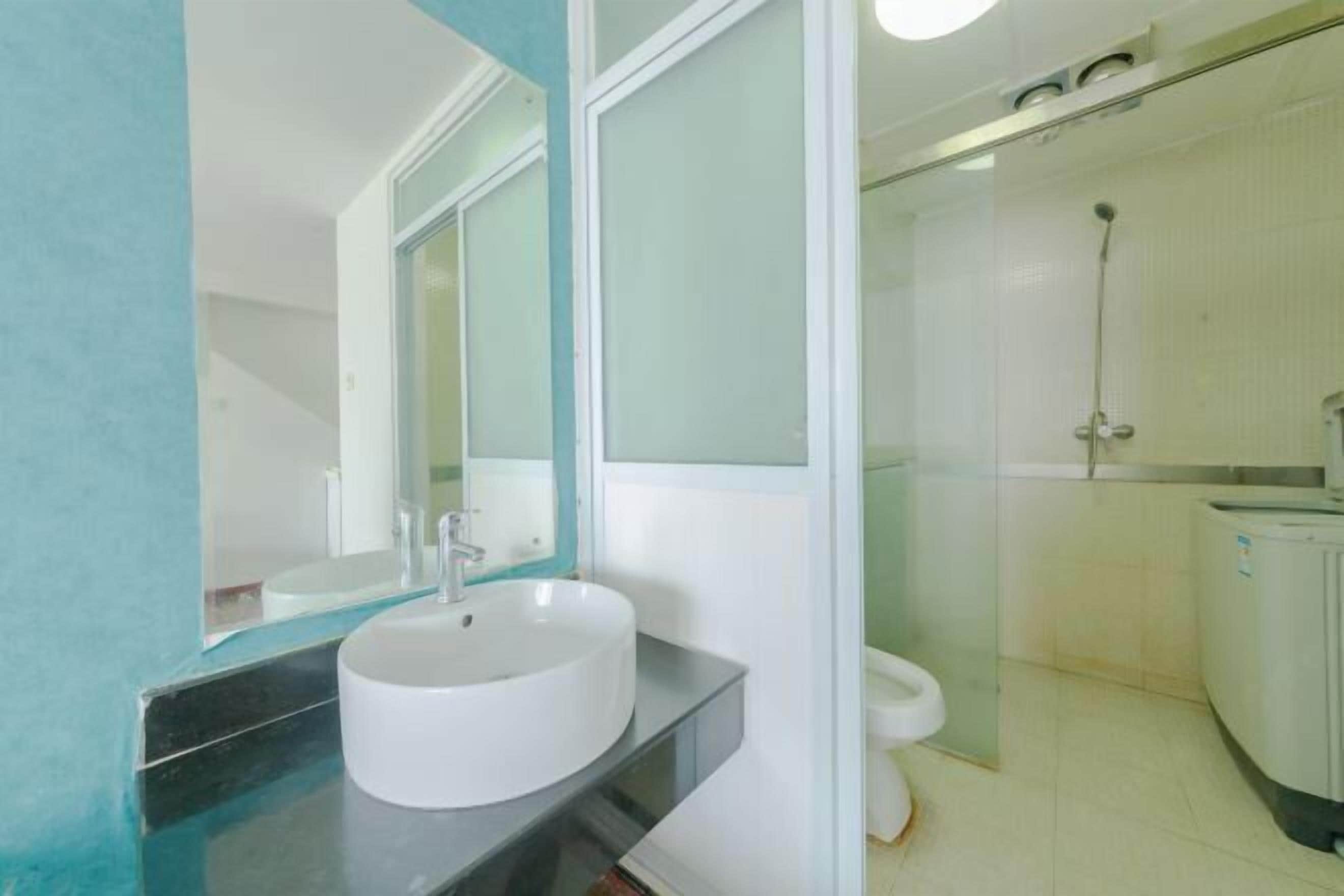 Ein modernes Badezimmer mit einem weißen Waschbecken, einem großen Spiegel und einer Duschkabine aus Glas.