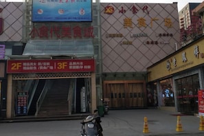 A commercial building with multiple storefronts, including a visible entrance with a ramp and a motorcycle parked outside.
