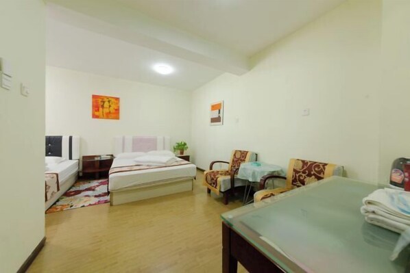 A hotel room with a bed, a small table, a chair, and a desk. - Seascape Boutique International Apartment (Xi'an)