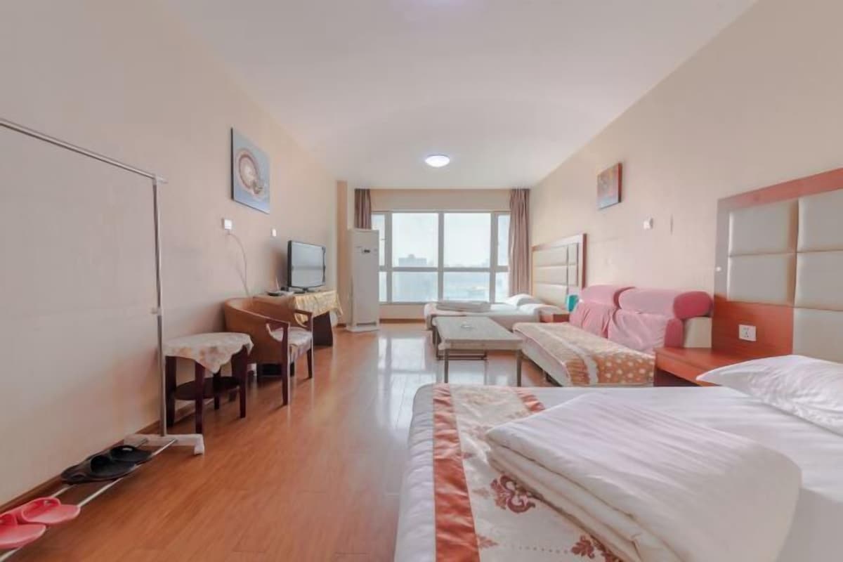 A hotel room with a bed, a desk, a chair, a TV, and a window.