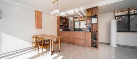 A modern kitchen with a wooden table and chairs, a built-in bookshelf, and a refrigerator.