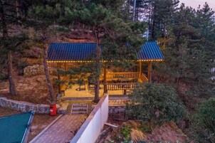 A gazebo with a blue roof, surrounded by trees, and a pool area in the foreground.