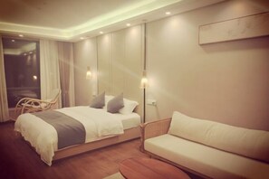 Une chambre d’hôtel moderne, équipée d’un lit, d’un canapé et d’un fauteuil.