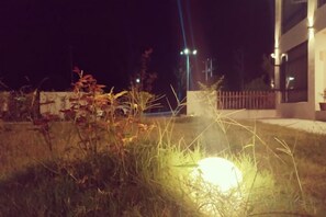 A nighttime outdoor area with a well-lit pathway, a fence, and a building in the background. - Baiyunjian Homestay (Qianshan)