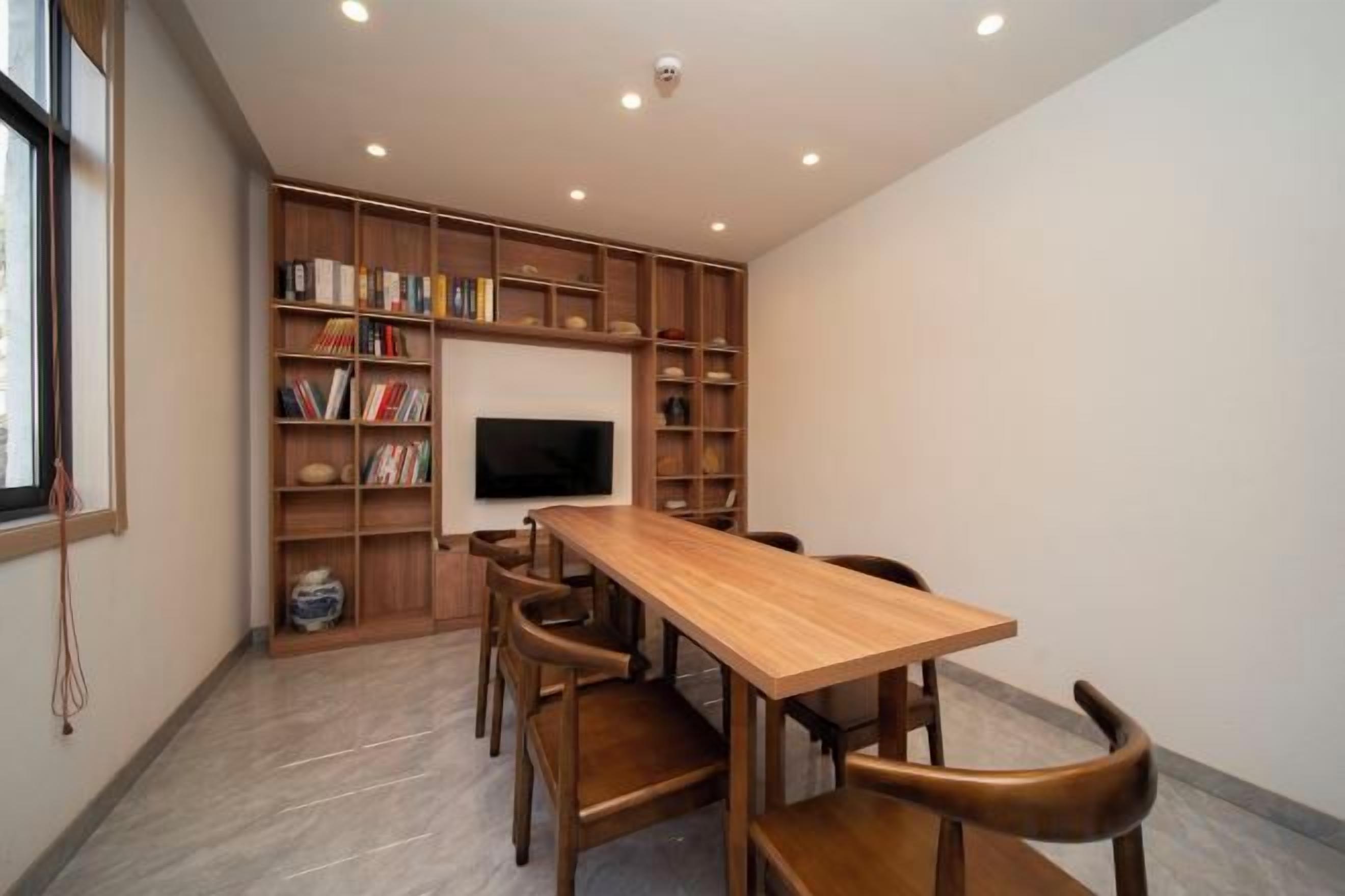 A room with a wooden table and chairs, a bookshelf, and a television.