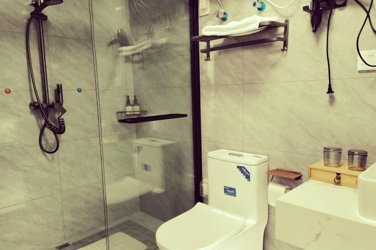 Une salle de bain moderne avec une douche à parois de verre, des toilettes blanches et un meuble-lavabo doté d’un porte-serviettes et de deux récipients en verre.