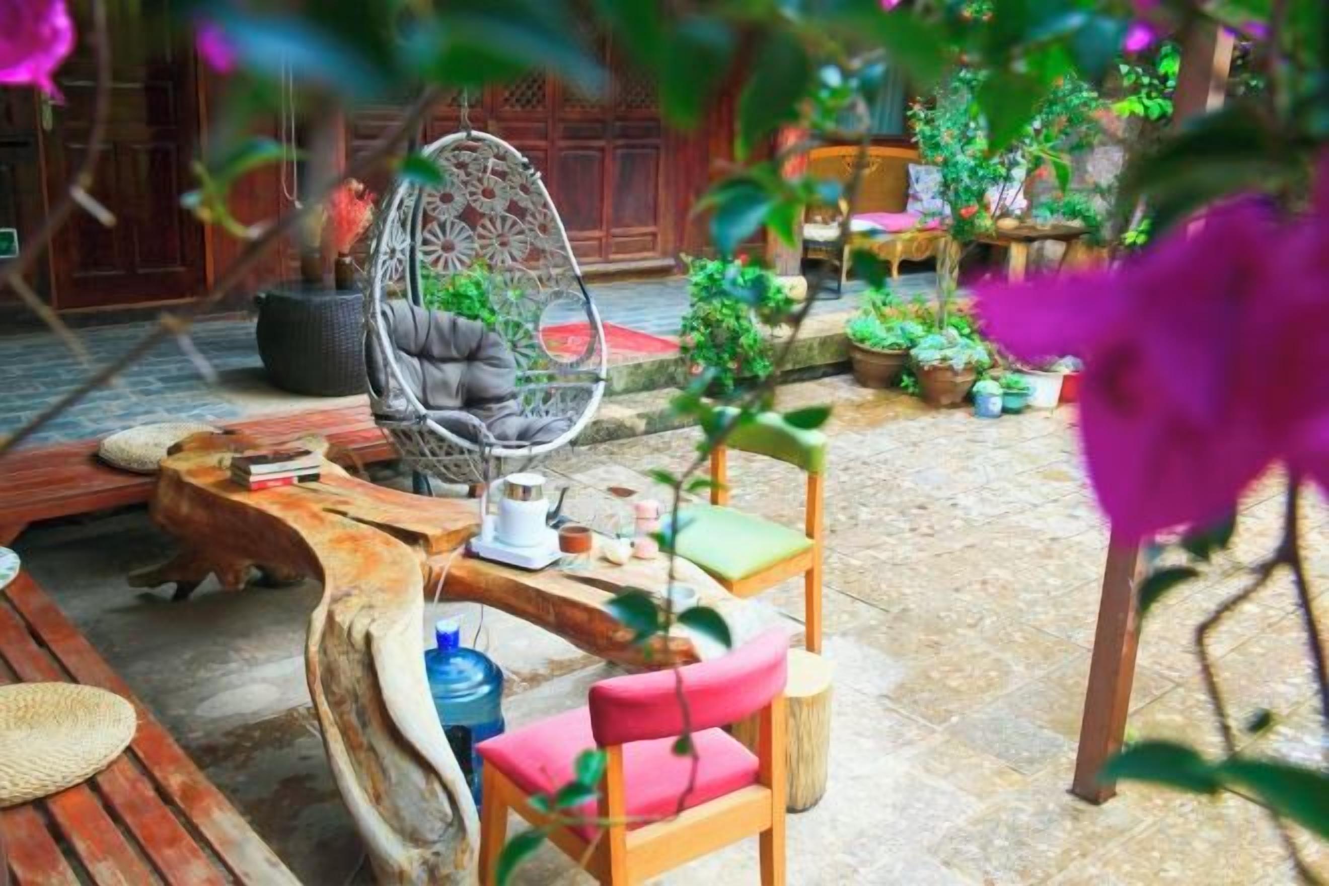 Un espacio al aire libre con mesa de madera, sillas y una butaca colgante.