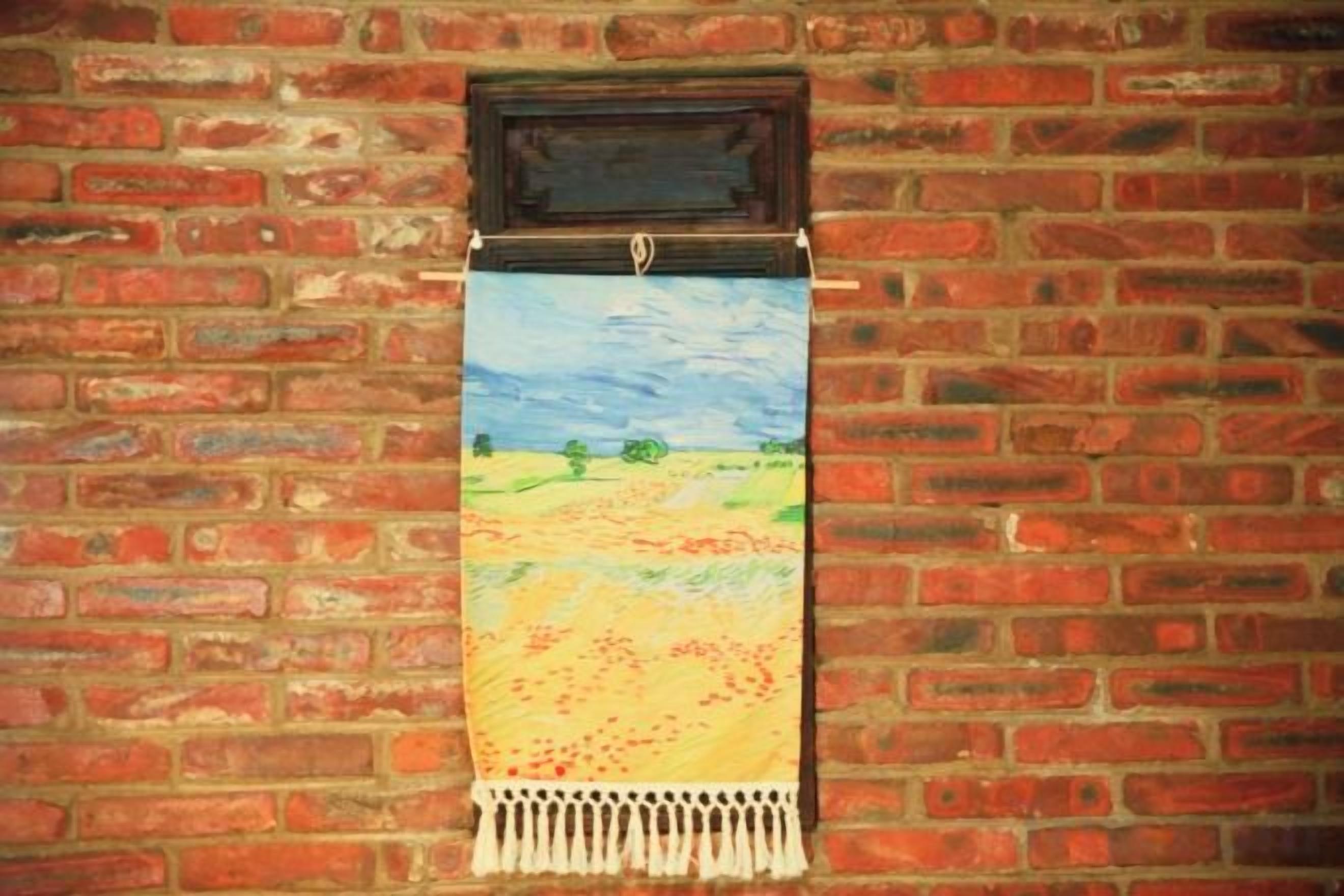 Une tapisserie est accrochée à un mur de briques.