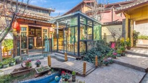Un bâtiment traditionnel doté d’une véranda en verre, d’un petit étang et de plantes en pot.