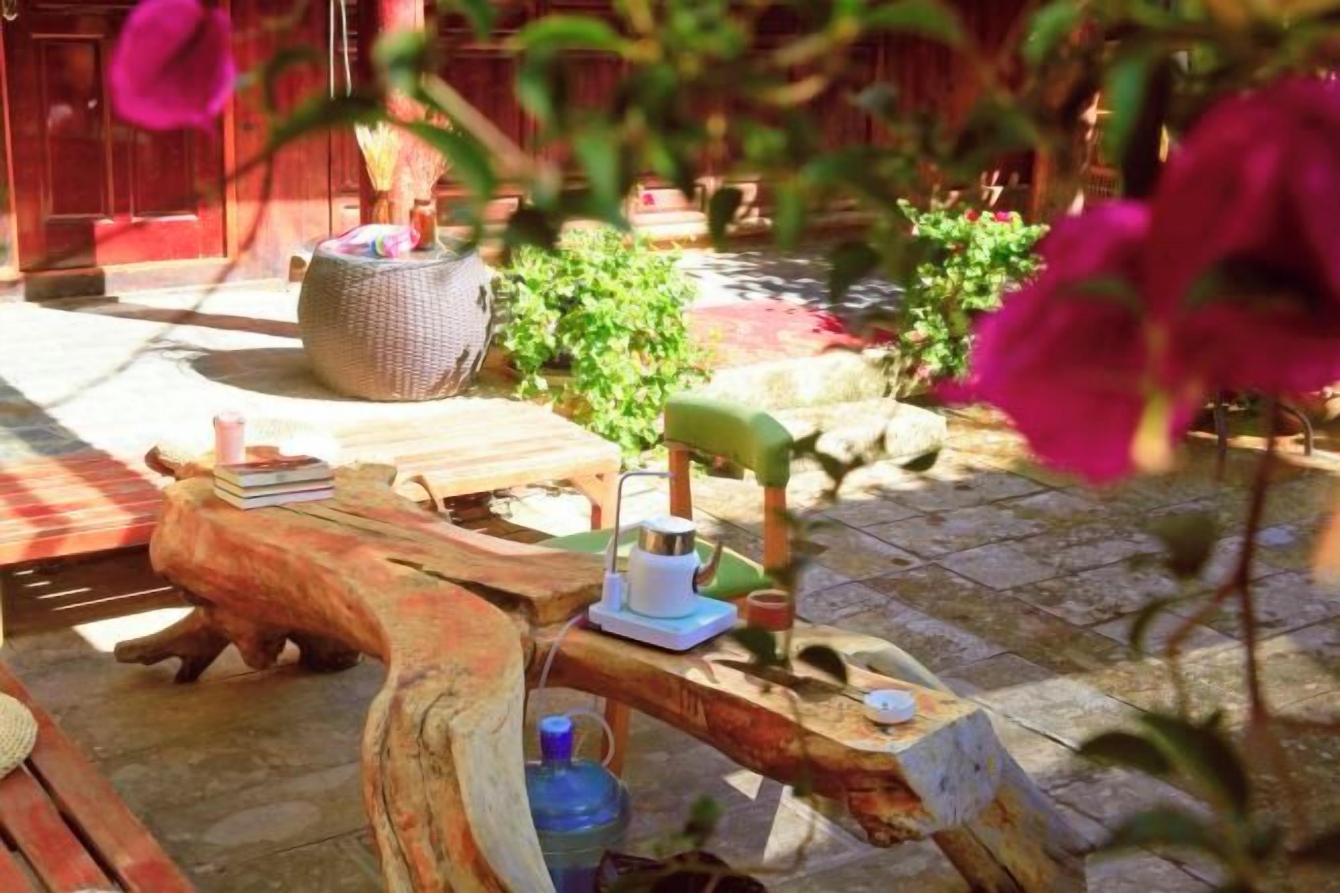 An outdoor seating area with a rustic wooden table, a woven basket, and a stone pathway.