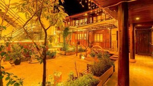 Un bâtiment rustique en bois, doté d’un balcon, de plantes en pot et de guirlandes lumineuses.