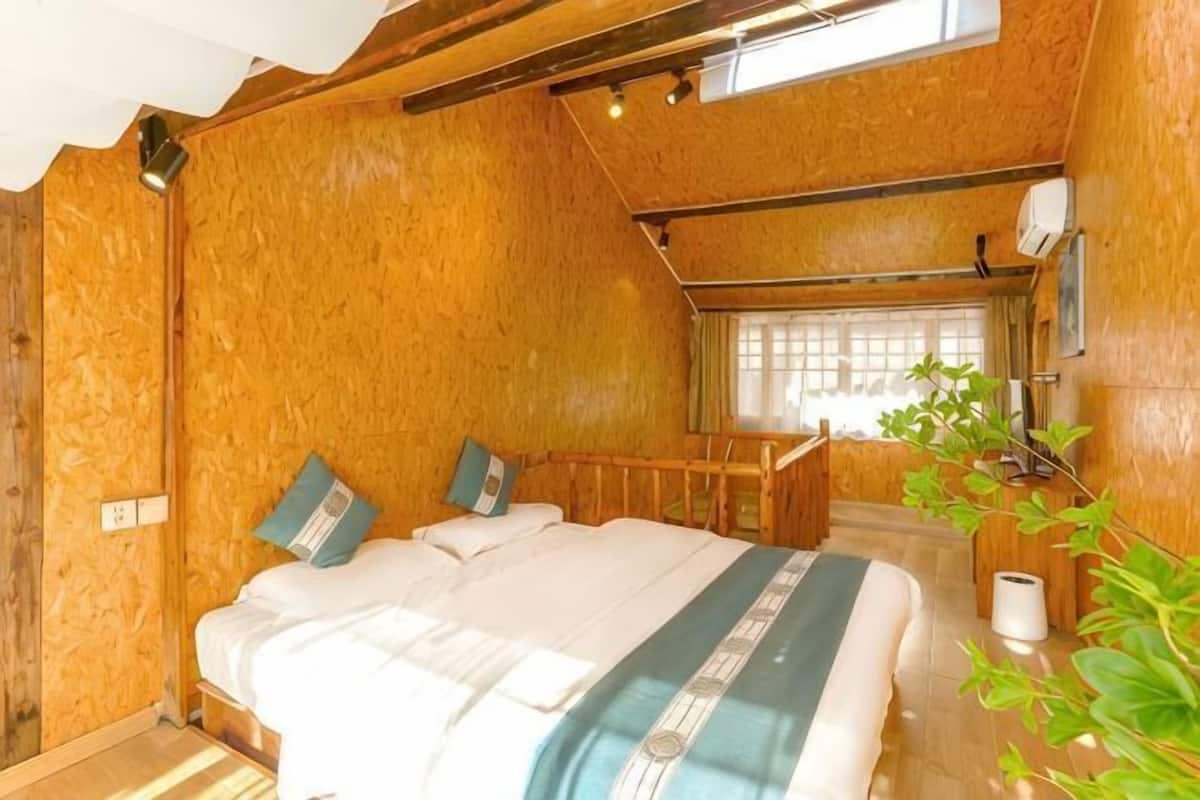 Ein Zimmer mit Holzboden, einem Bett, einem Fenster und einer Pflanze.