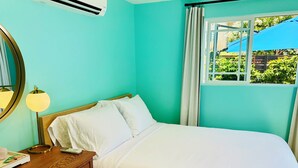 A bedroom with a bed, a bedside table, a lamp, a mirror, and a window with curtains. - South Park Hideaway (San Diego)