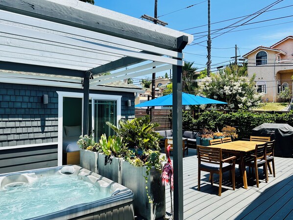 Une terrasse dotée d’un jacuzzi, d’un espace salon extérieur et d’une pergola.