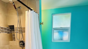 A bathroom with a shower, a toilet, and a window. - South Park Hideaway (San Diego)