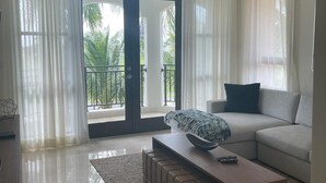 A modern living room with a sofa, a coffee table, and a view of a balcony with palm trees. - Otium Serene Modern Pool Nice Balcony (Río Grande)
