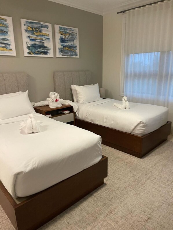 Une chambre d’hôtel avec deux lits, une table de chevet et des œuvres d’art accrochées au mur.