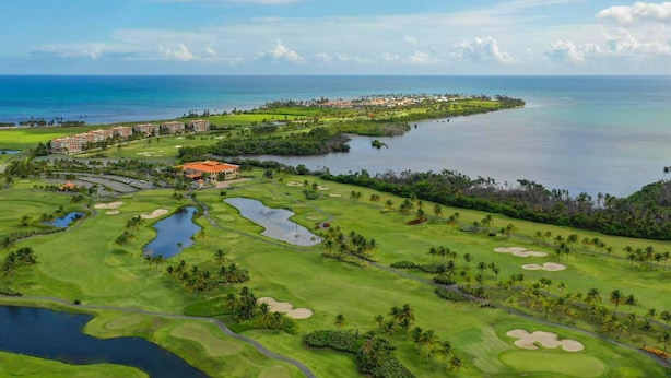 A golf course with multiple water hazards, a clubhouse, and a view of the ocean. - Otium Serene Modern Pool Nice Balcony (Río Grande)