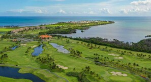 Un parcours de golf comportant de nombreux obstacles d’eau, un club-house et une vue sur l’océan.