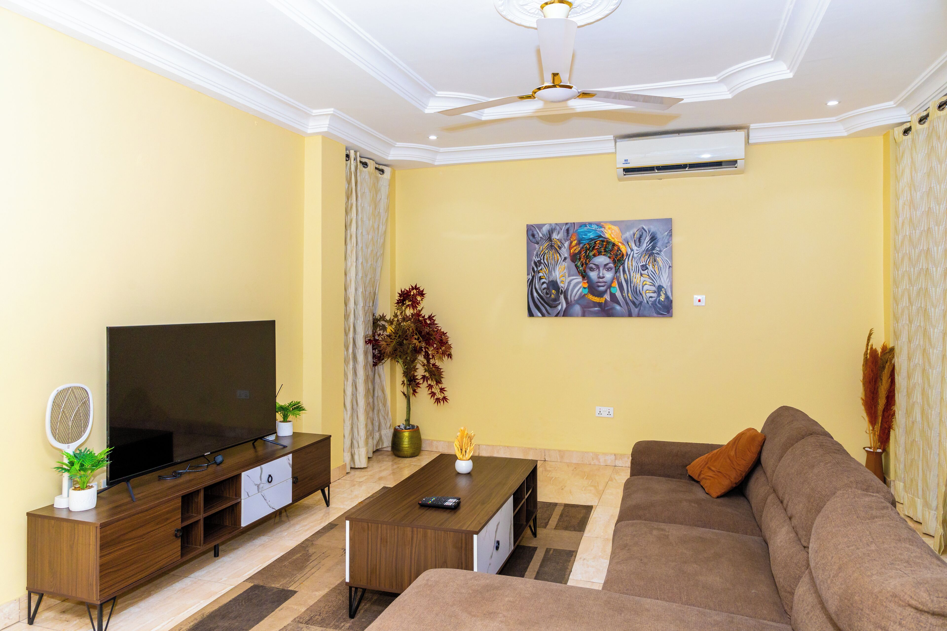 A living room with a flat-screen TV, a sofa, a coffee table, and a painting on the wall.