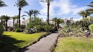 A paved pathway flanked by palm trees and cacti, leading to a building with a white facade and red-tiled roof. - Home2Book Cozy Pool & Terrace Apartment, Arona (Arona)