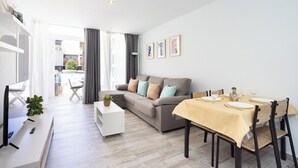 A modern living room with a sofa, dining table, and a TV. - Home2Book Cozy Pool & Terrace Apartment, Arona (Arona)