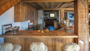 Eine rustikale Küche mit Holzbalken, einer Holzinsel inklusive Barhocker und einem gerahmten Bild auf der Arbeitsfläche.