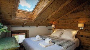 Ein Zimmer mit Holzboden, einem Bett, zwei Nachttischlampen und einem Oberlicht.
