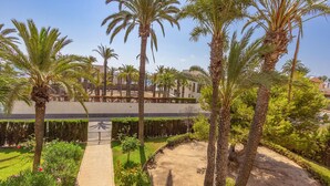 A landscaped garden with palm trees, a paved walkway, and a building in the background. - Awesome apartment in Torrevieja with WiFi (Torrevieja)