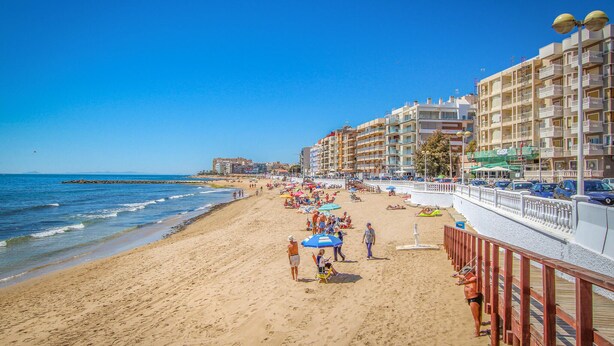 A beach with a promenade, beach umbrellas, and a row of multi-story buildings. - Awesome apartment in Torrevieja with WiFi (Torrevieja)