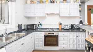 A kitchen with white cabinetry, a double sink, a microwave, a toaster, and a coffee maker. - Villa Kernow - comfortable 3 bedroom villa (Moraira)