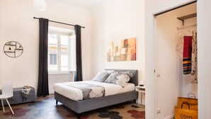 A bedroom with a bed, a chair, a wardrobe, and a window with curtains. - Idyllia | Vatican Stylish Flat (Roma)
