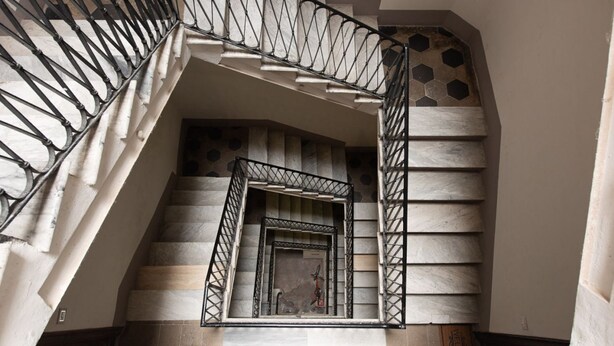 A staircase with a metal railing and a view of a door at the bottom. - Idyllia | Vatican Stylish Flat (Roma)