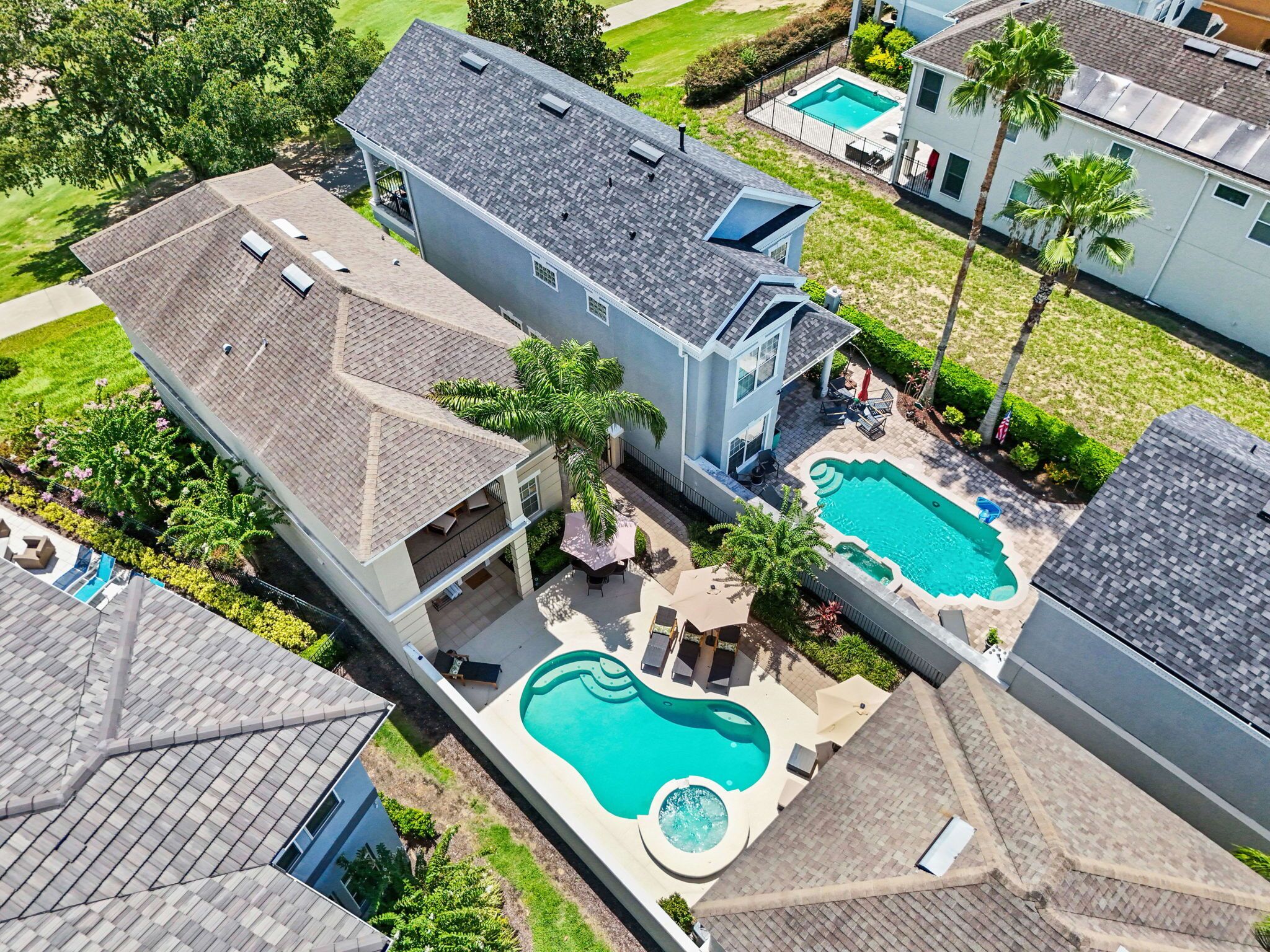 Una propiedad residencial con una amplia piscina, varias terrazas y un césped bien cuidado.