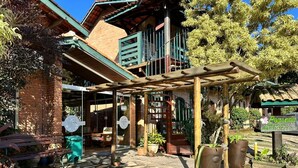 A building with a covered patio area, outdoor seating, and potted plants. - Pousada Refúgio Manacás (Ubatuba)