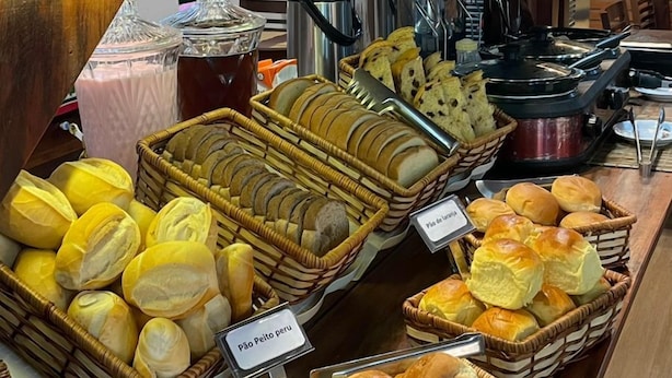 A bakery display with various baked goods and a coffee station. - Pousada Refúgio Manacás (Ubatuba)