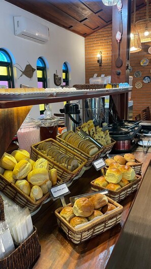 A bakery display with various baked goods and a coffee station. - Pousada Refúgio Manacás (Ubatuba)