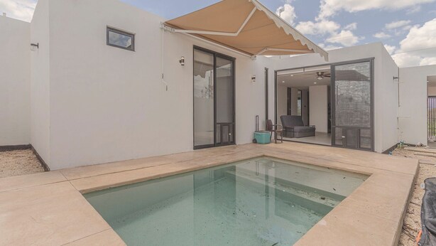 A modern house with a swimming pool, a covered patio, and a glass door leading to an indoor living area. - New Merida Retreat with Private Pool (Mérida)