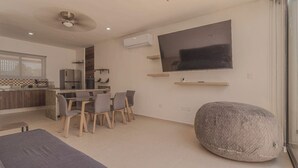A modern kitchen with a dining area, a large TV, and a stone accent piece. - New Merida Retreat with Private Pool (Mérida)